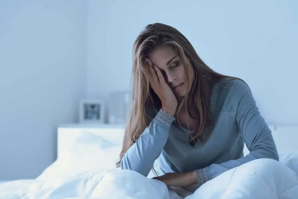 Withdrawing from meth, a woman awake in the night, she is touching her forehead and suffering from insomnia