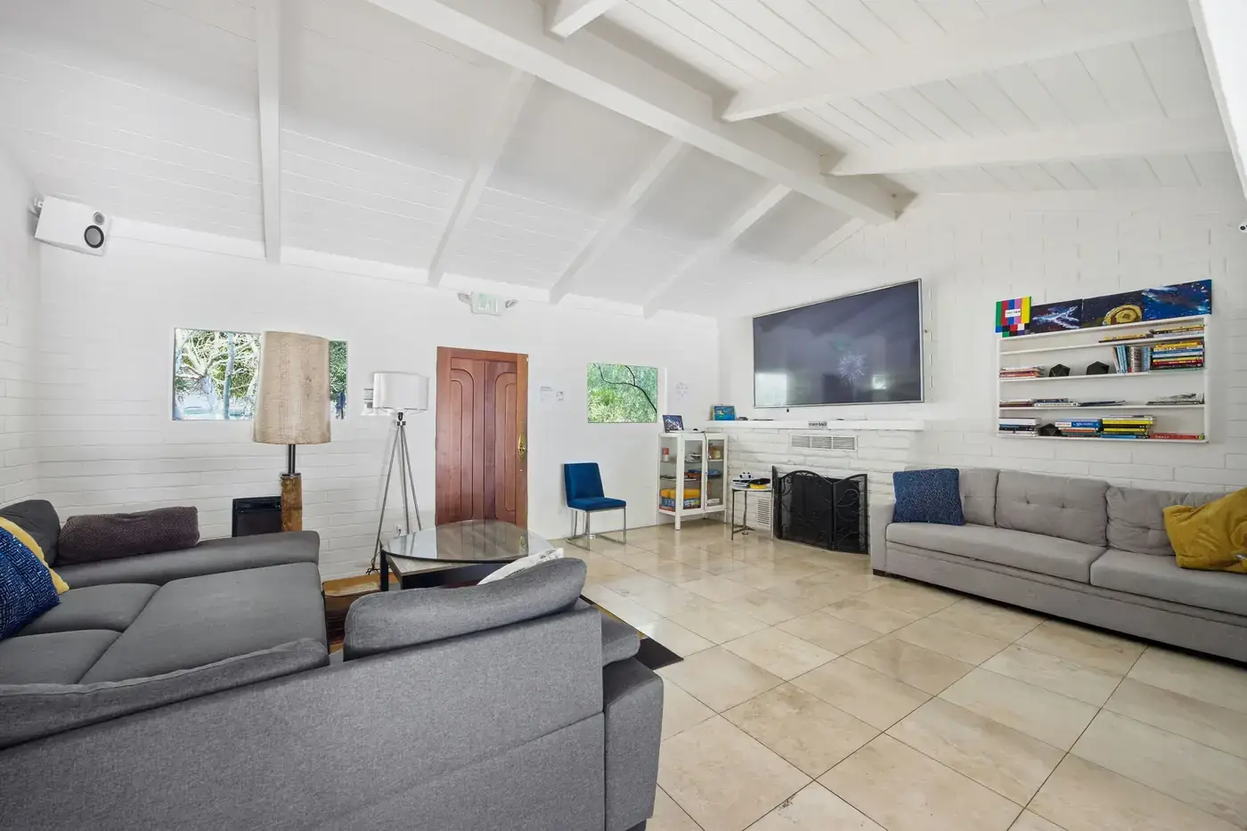 Living room with sofas, a large TV, a fireplace and bookshelves